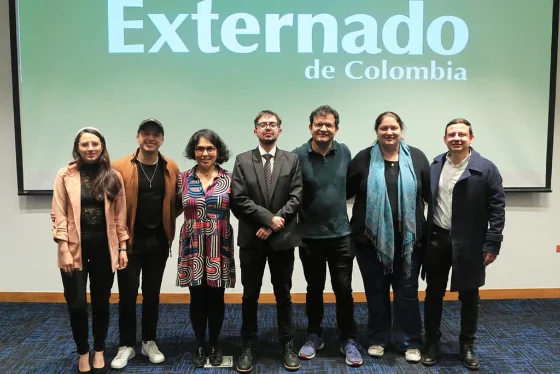 Andrés Yañez con un grupo de personas frente a una pantalla de la Universidad Externado de Colombia
